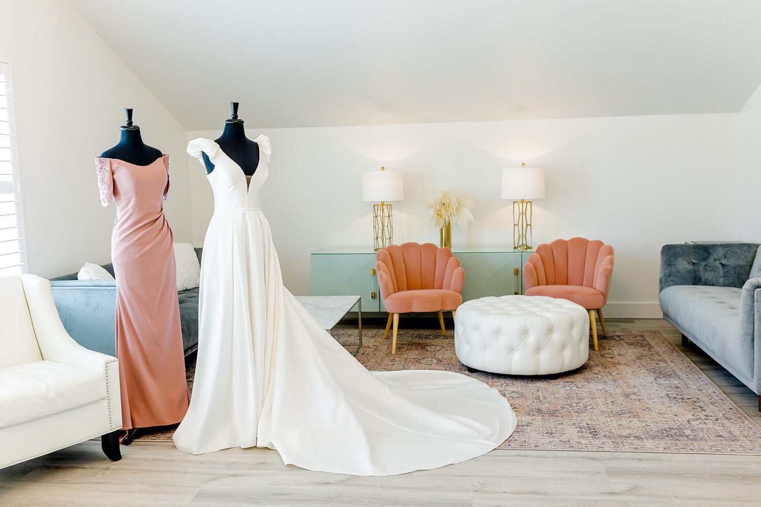 The brides gown side by side with one of the brides maids gowns in the bridal suite.